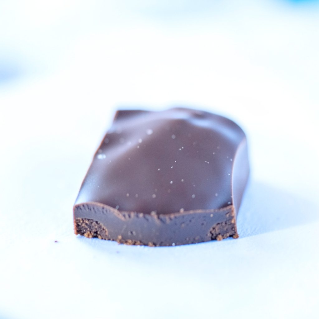 A rich chocolate-brown textured surface photographed in warm light, with gentle shadows emphasizing depth and a premium, handcrafted feel.
